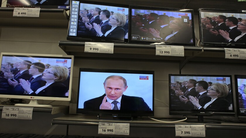 Russian President Vladimir Putin, shown on a TV screen in a Moscow shop, delivers his state of the nation address.