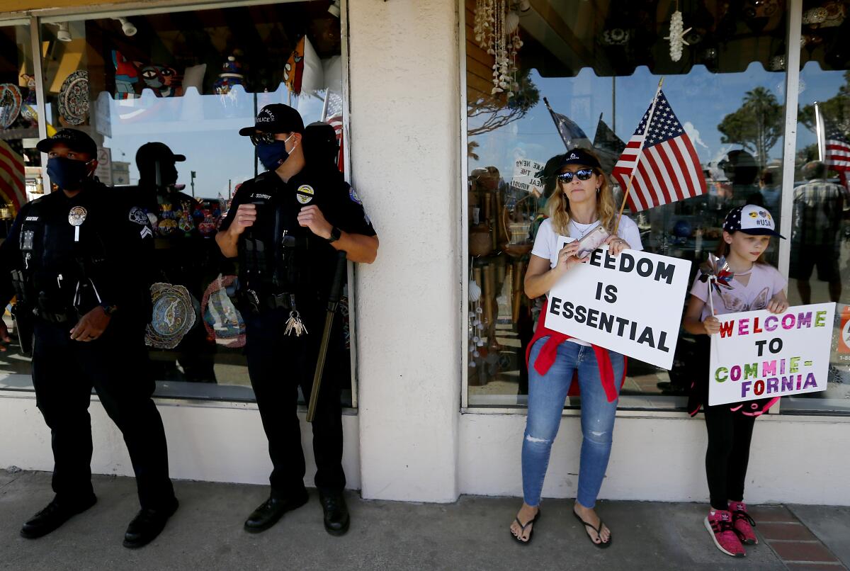 Policías y manifestantes se protejen del sol el sábado en Pacific Coast Highway en Laguna Beach.