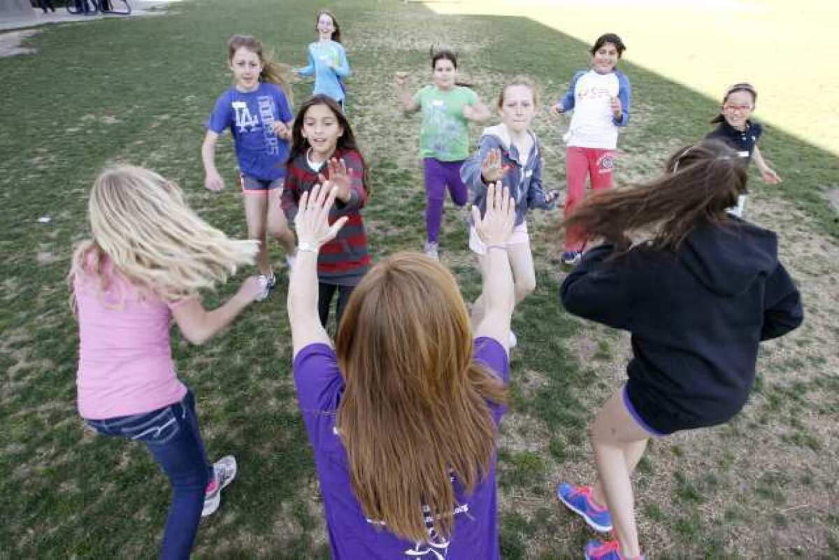 Participants in the Girls on the Run program high five program leader Leanne Lowden Mothershead during a warm up excercise.
