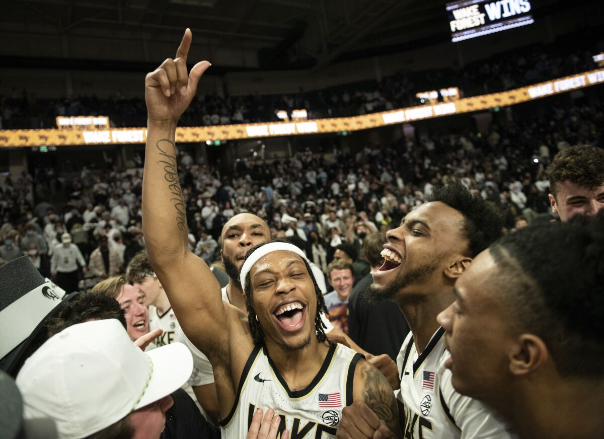 FILE - Wake Forest guard Alondes Williams, center left, and forward Isaiah Mucius, center right, celebrate as students storm the court following the team's 98-76 victory over North Carolina in an NCAA college basketball game Saturday, Jan. 22, 2022, in Winston-Salem, N.C. Alondes Williams is The Associated Press men’s basketball player of the year for the Atlantic Coast Conference, announced Tuesday, March 8, 2022. (Allison Lee Isley/The Winston-Salem Journal via AP, File)