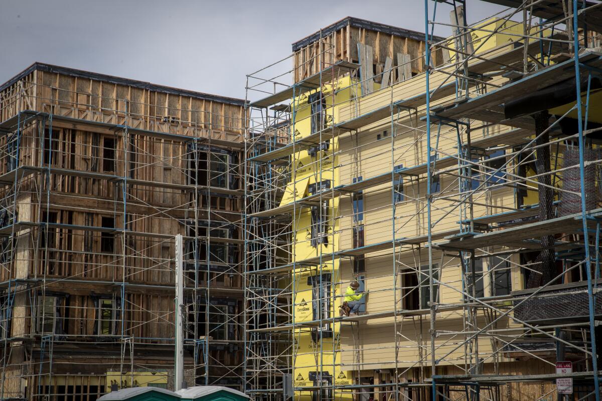 Construction workers work on scaffolding around buildings.