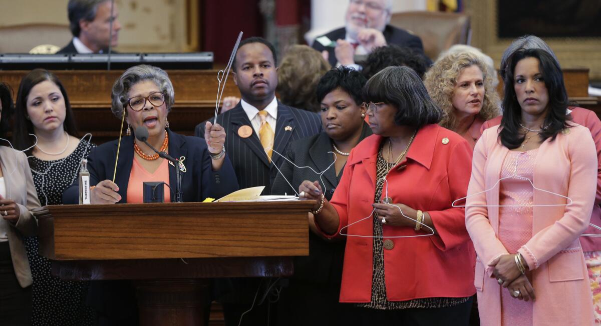 Rep. Senfronia Thompson, D-Houston, second from left, holds a coat hangar as she stands with fellow representatives while proposing an amendment to the second reading of HB 2, legislation that will restrict abortion rights, on the Texas House floor Tuesday in Austin. The Texas House is expected to vote on the bill Tuesday.