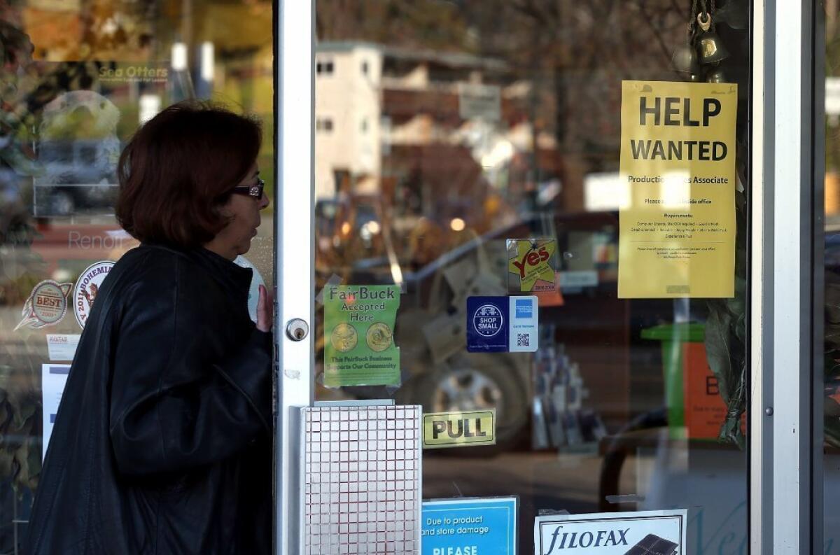 A woman enters a store with a help wanted sign posted on the door Fairfax, Calif.