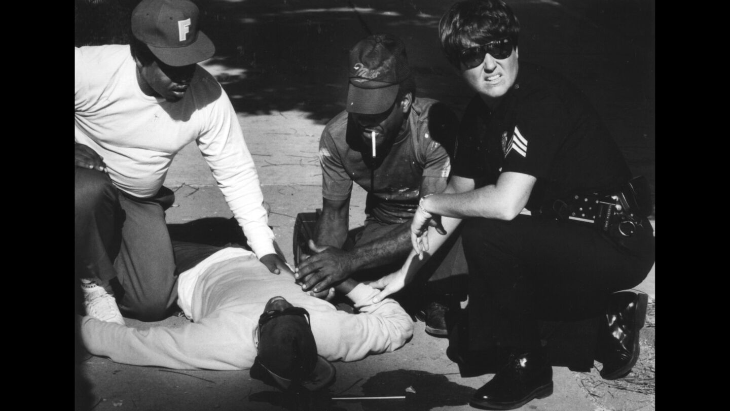 Los Angeles Police Sgt. Terry Tatreau looks over a gang member who was shot in the head by an East Coast Crip at 79th Street and San Pedro.