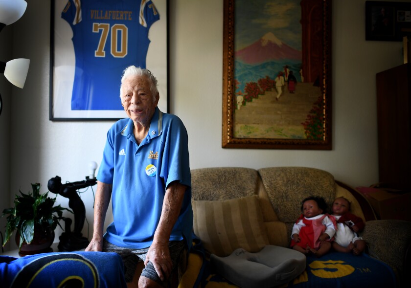 UCLA fan George Villafuerte sits in the living room of his apartment in Reseda.