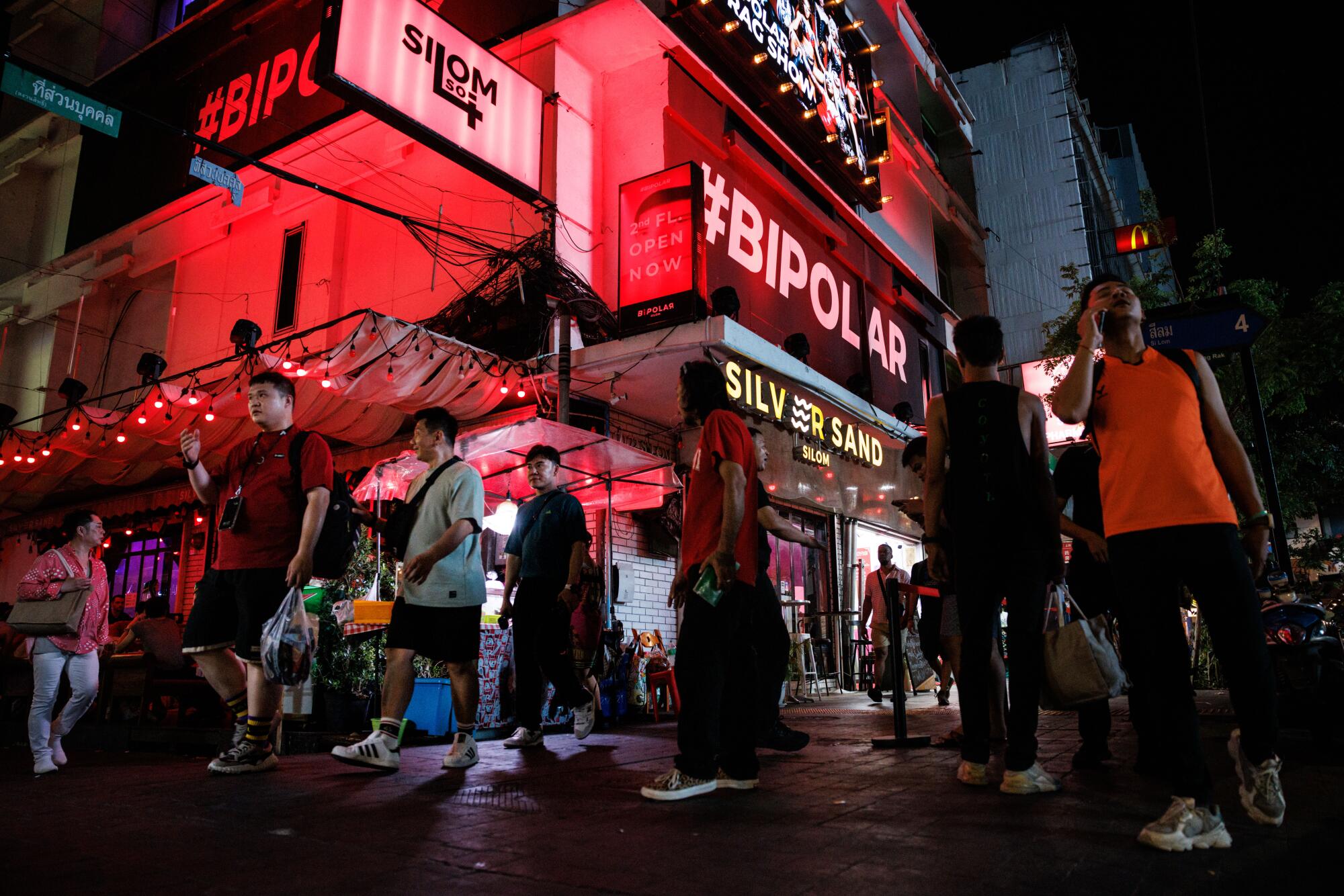 People walk past #Bipolar and Silver Sand, popular bars on Silom Soi 4, a street known f