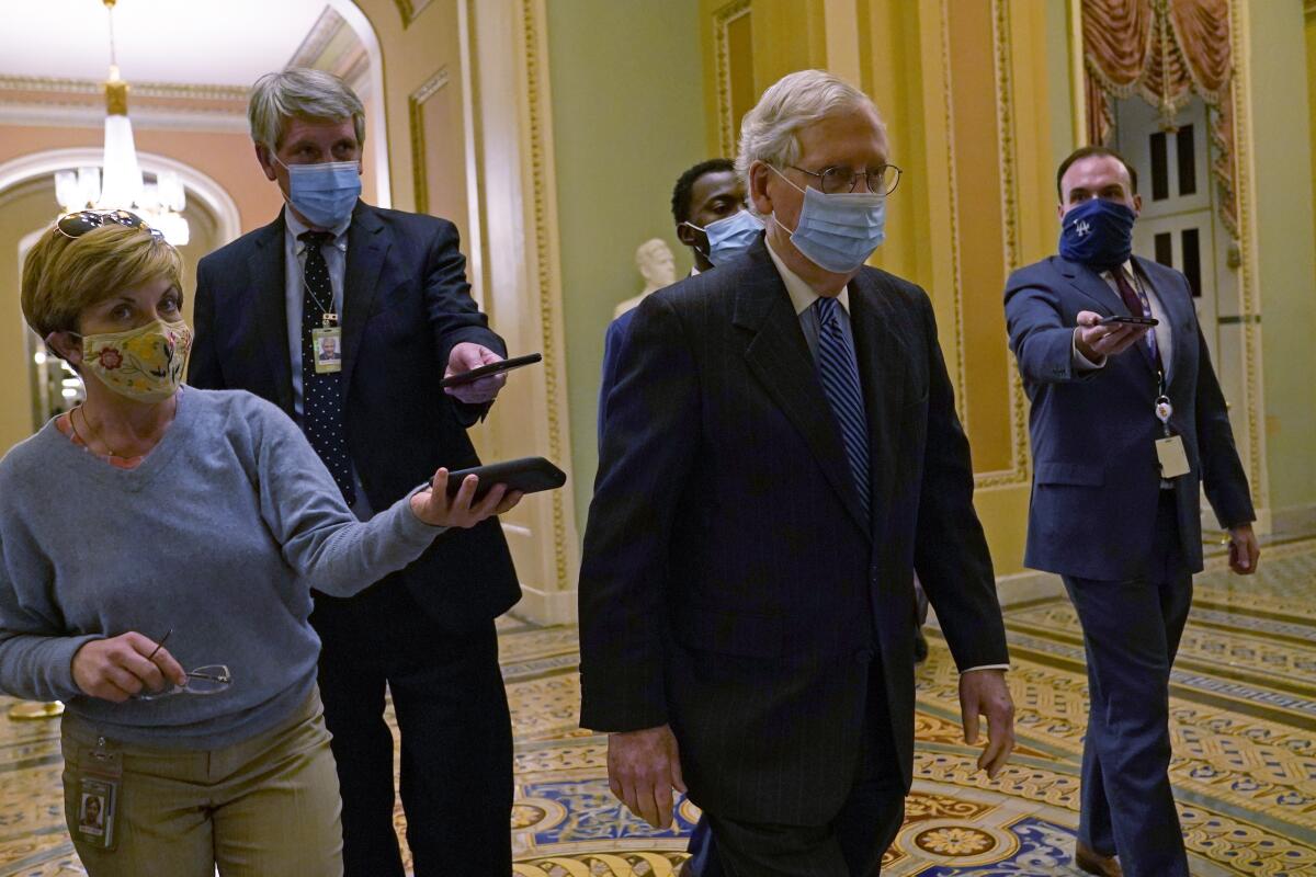 Senate Majority Leader Mitch McConnell walks through the Capitol, followed by reporters