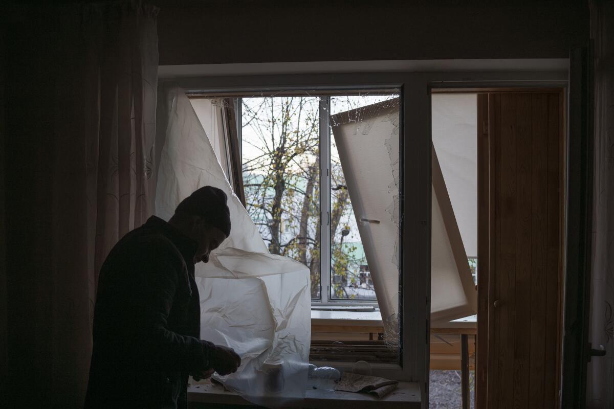Man using plastic to cover broken window in his apartment in Kyiv, Ukraine