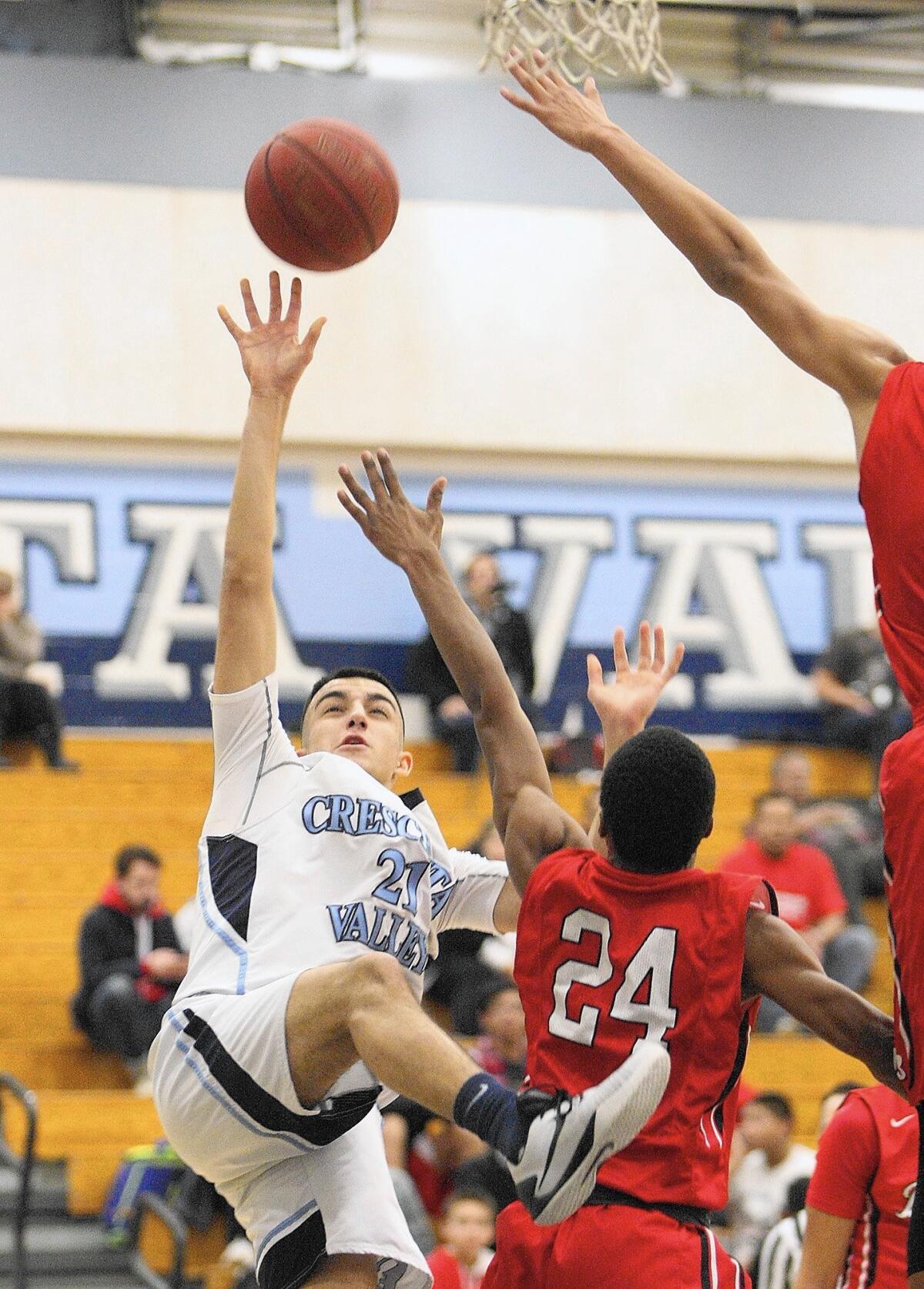 Crescenta Valley High's Arin Ovanessian goes up for a shot against the defense of Burroughs High's Nick Howard during a game on Tuesday, Jan. 5, 2016.