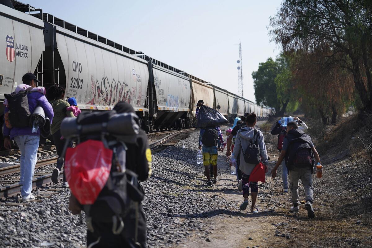 Migrantes caminan junto a un tren con dirección al norte