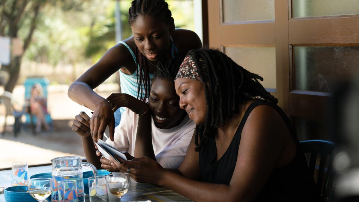 three women smile as they look at pieces of paper