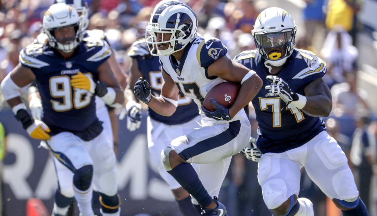 Chargers defensive linemen Damion Square (71) and Isaac Rochell (98) try to track down Rams receiver Robert Woods during their game Sunday.