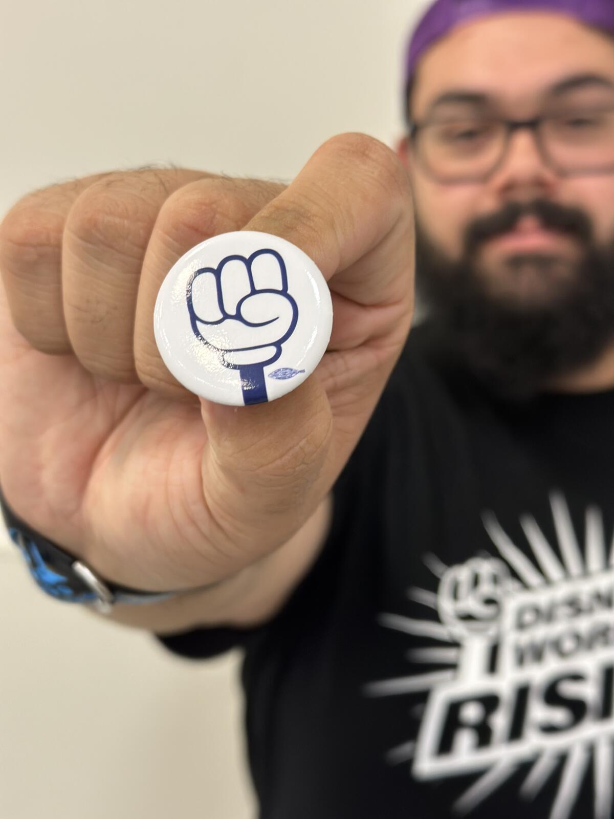 Daniel Rodriguez, a Disneyland custodian, holds the union button that got him a warning at work.