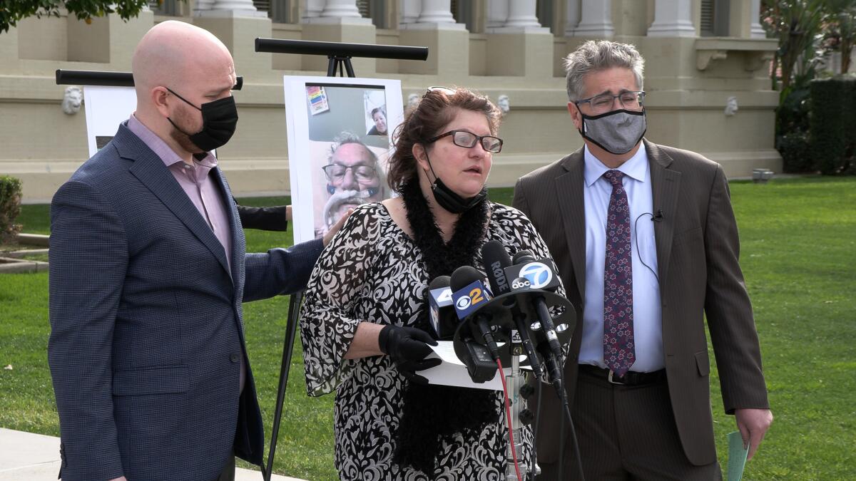 A woman speaks into TV news microphones at an outdoor news conference