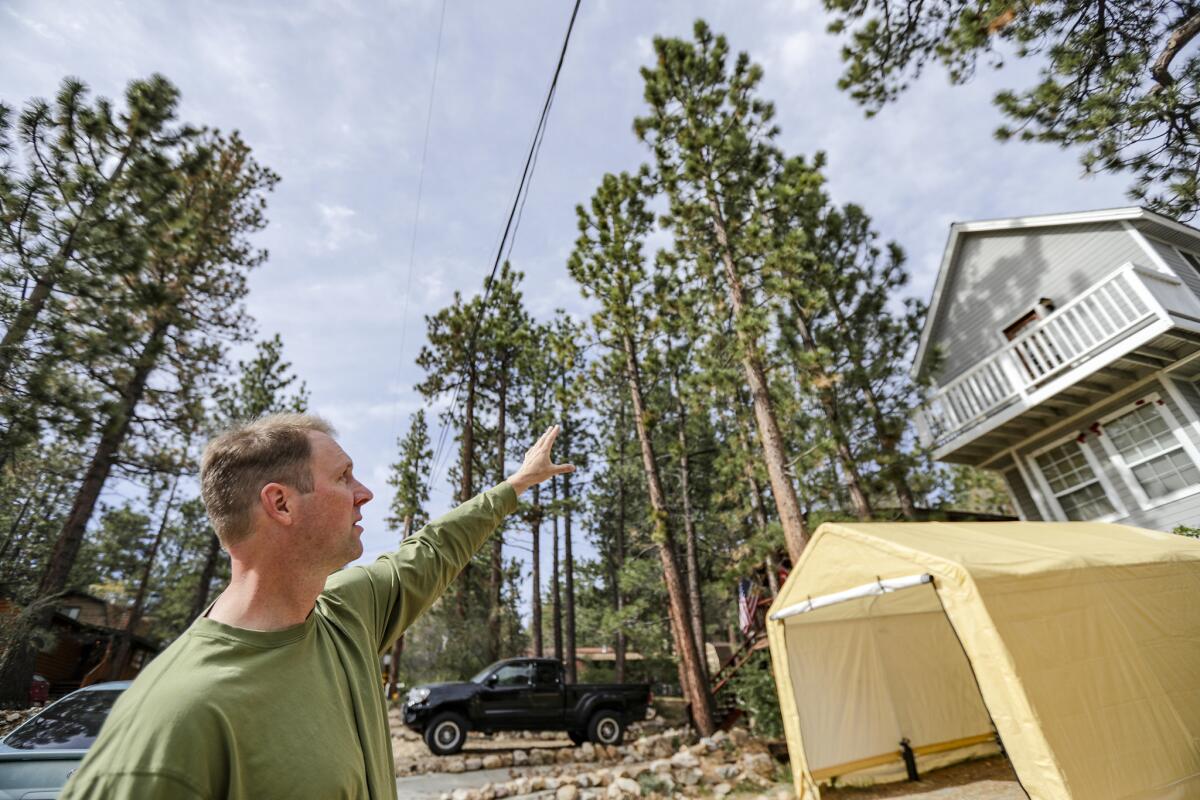 Chad Hanson, executive director and research ecologist at John Muir Project of Earth Island Institute, points to extreme fire danger because of overgrown grasses and trees very close to and hanging over structures in the residential community of Sugarloaf near Big Bear.