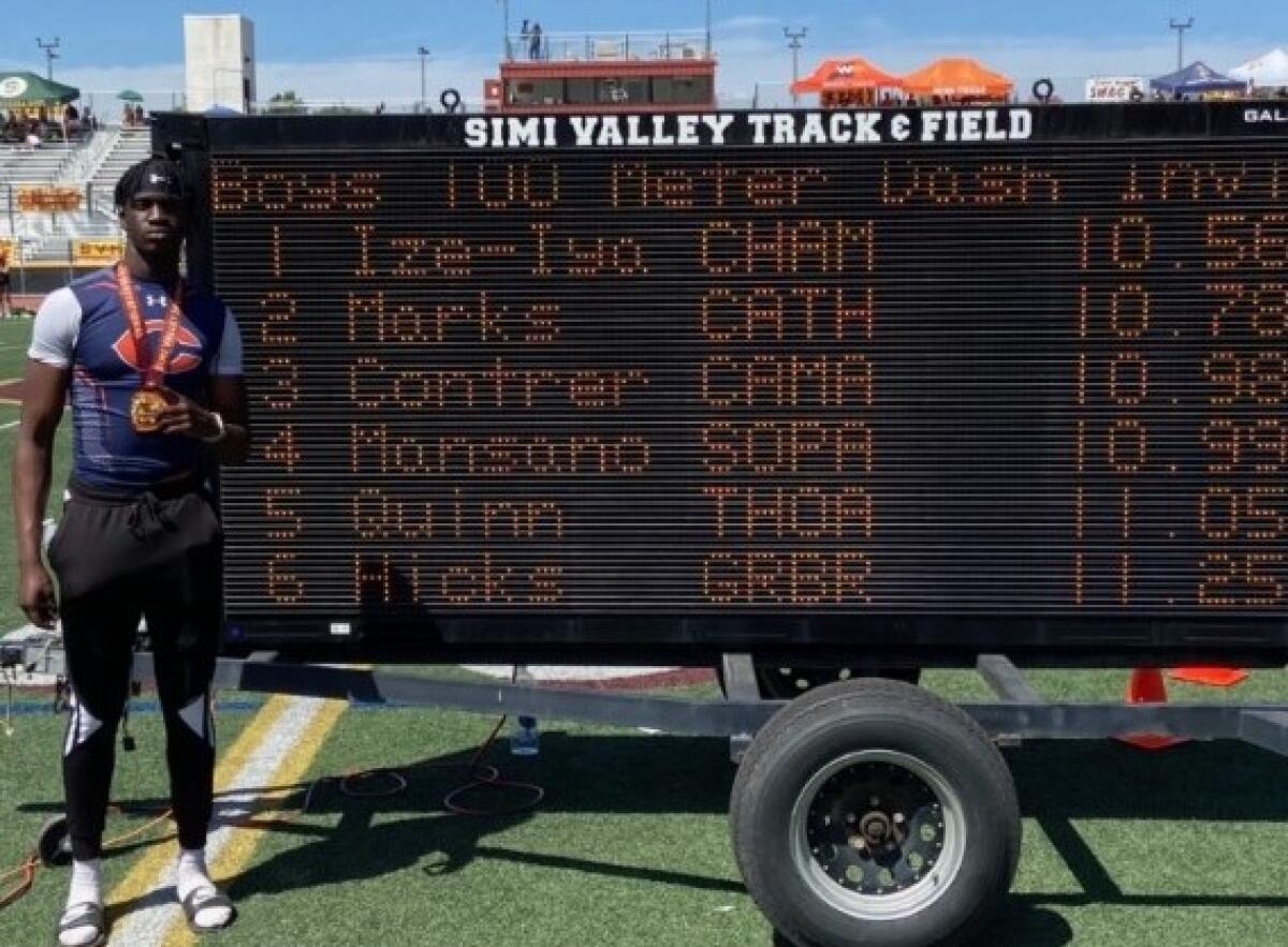 Patrick Ize-Iyamu of Chaminade poses in front of the scoreboard after running 10.56 100 meters at Simi Valley Invitational.