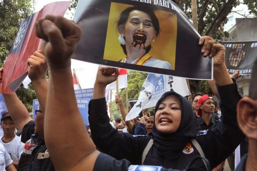 A Muslim woman shouts slogans as she holds up a poster bearing a defaced portrait of Myanmar's leader Aung San Suu Kyi during a rally against the persecution of the Rohingya Muslim minority, outside the Myanmar's Embassy in Jakarta, Indonesia, Monday, Sept. 4, 2017. Hundreds of people staged the rally in the third day of protests calling for the government of the world's most populous Muslim country to take a tougher stance against persecution of the Rohingya. (AP Photo/Tatan Syuflana)