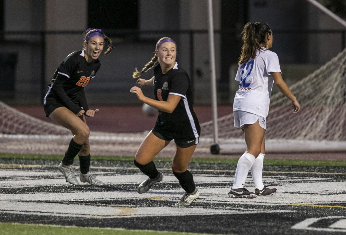 Huntington Beach's Hannah Petteys, center and Solana Van Enoo, left, celebrate a goal by Petteys during Monday's match.