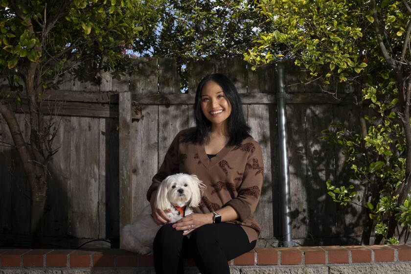 Tracy Badua, holds her dog, Sandy, outside her home in San Diego 