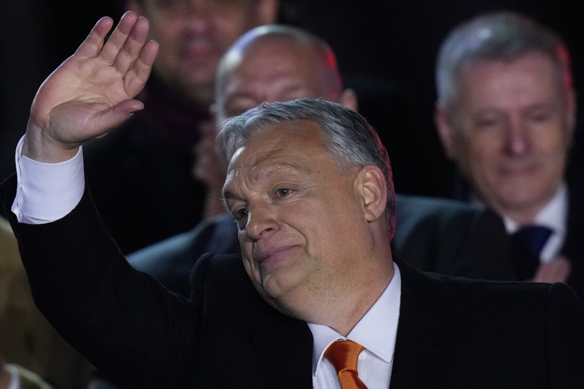 Hungary's Prime Minister Viktor Orban greets cheering supporters during an election night rally in Budapest, Hungary, Sunday, April 3, 2022. Early partial results in Hungary's national election are showing a strong lead for the right-wing party of pro-Putin nationalist Orban as he seeks a fourth consecutive term. (AP Photo/Petr David Josek)