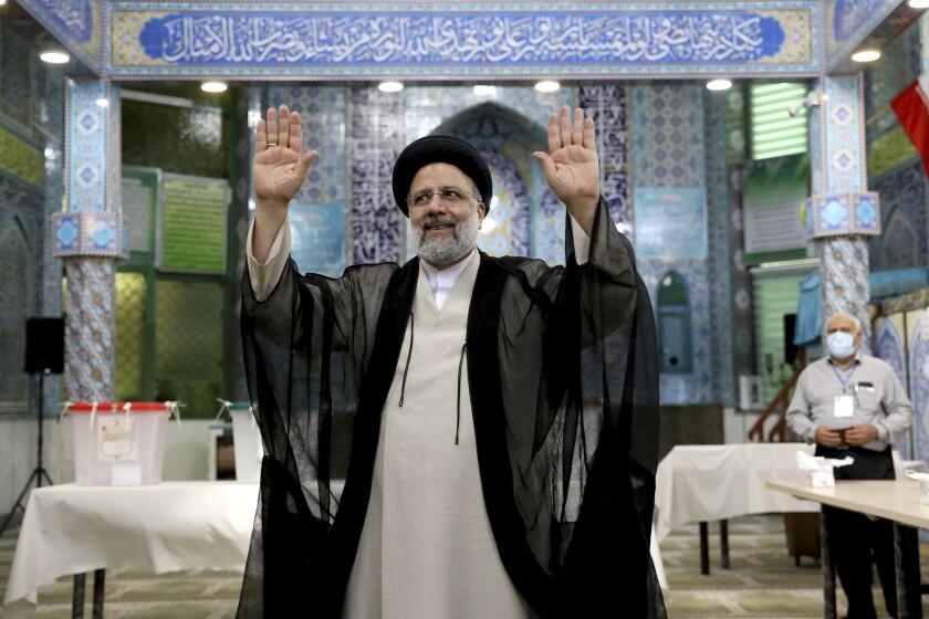 Ebrahim Raisi faces the camera, palms raised, after casting his vote