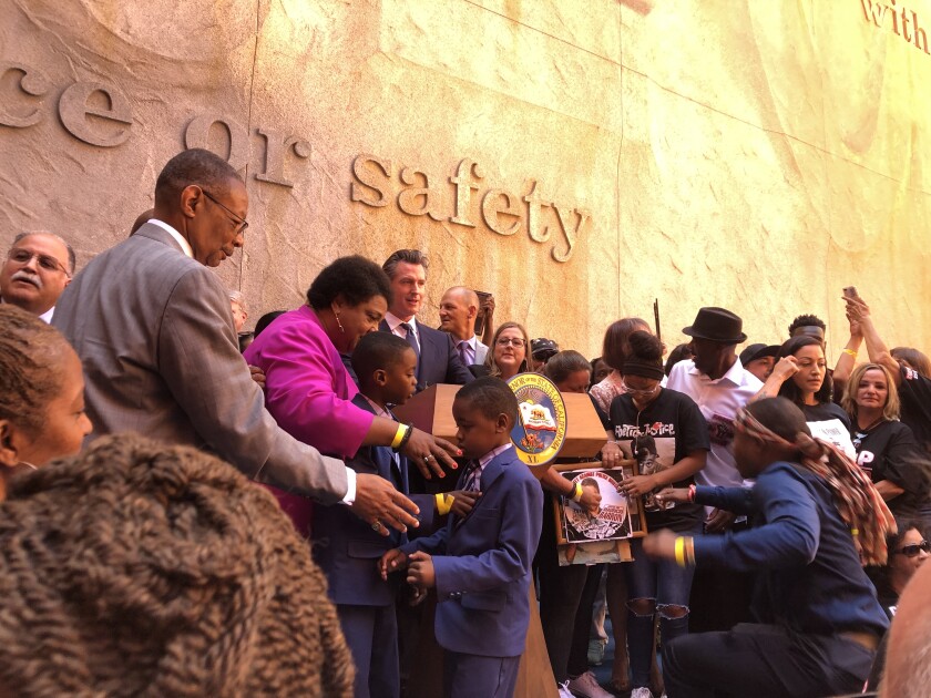 Gov. Gavin Newsom, Assemblywoman Shirley Weber and others gather on stage with families who have lost a loved one to police violence as the governor signs into law AB 392, a reform of California's use-of-force rules for law enforcement, on Monday, Aug. 19, 2019.