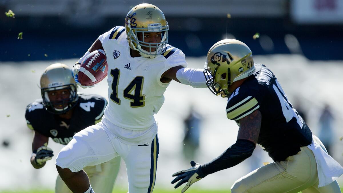 UCLA wide receiver Mossi Johnson, left, stiff-arms Colorado defensive back Terrel Smith after making a catch during the first half of Saturday's game.
