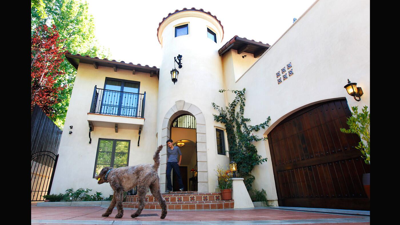 Architect John Lesak helped Greg and Jerilyn Chun transform their 1960 kit house into a 2,600-square-foot Spanish Colonial Revival home complete with tower. Their son Hamilton, 13, plays catch with Odie in front of the house.