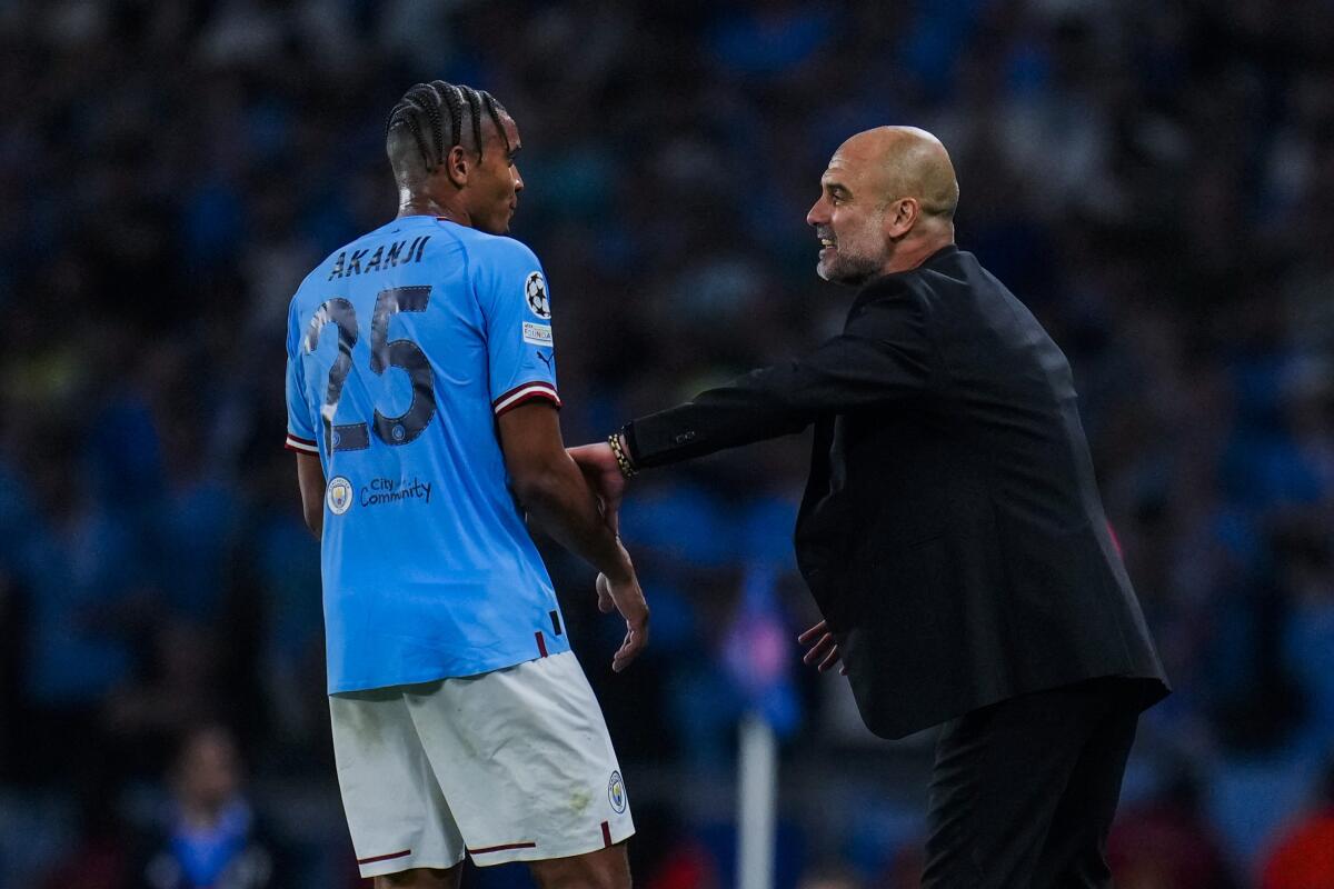 Manchester City's head coach Pep Guardiola talks to Manuel Akanji.