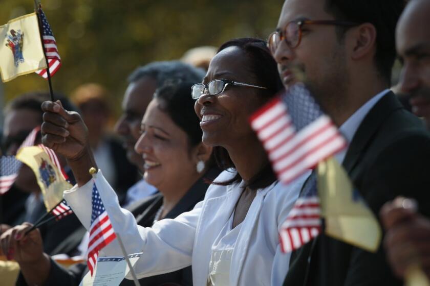 New American citizens wave flags after taking the oath of citizenship last month at Liberty State Park in New Jersey.