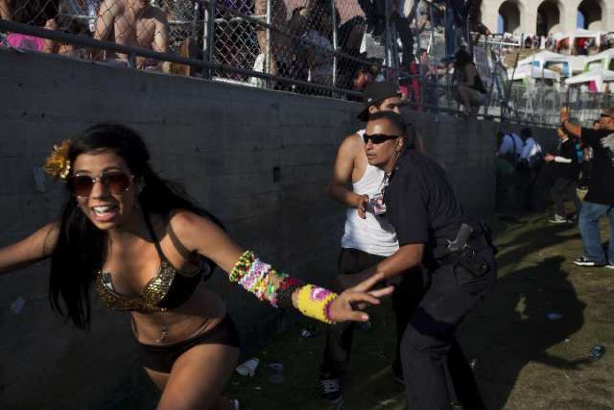 A woman runs from a police officer after several crowds rushed a fence at the Electric Daisy Carnival rave at Los Angeles Memorial Coliseum.