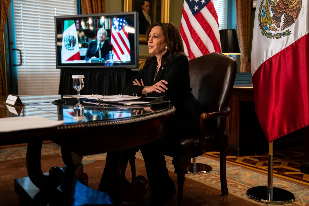 Kamala Harris sits at the head of a conference table.