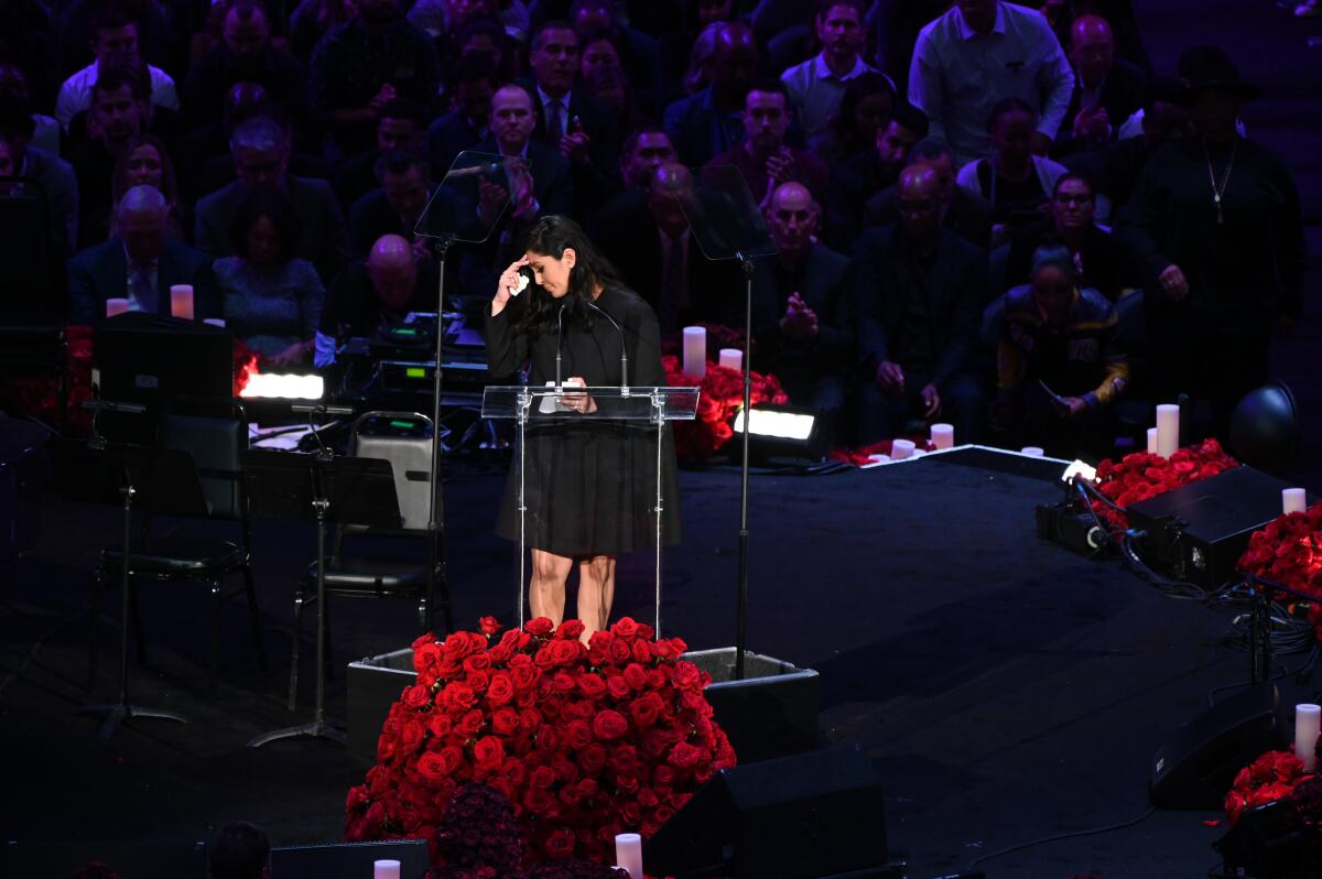 Vanessa Bryant bows her head in front of a bouquet of flowers onstage at Staples Center memorial