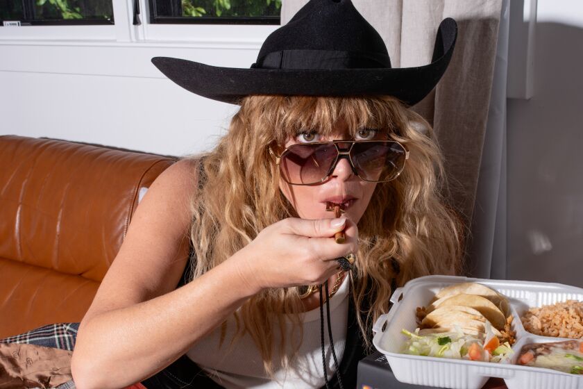 A woman leans over a table eating Mexican food