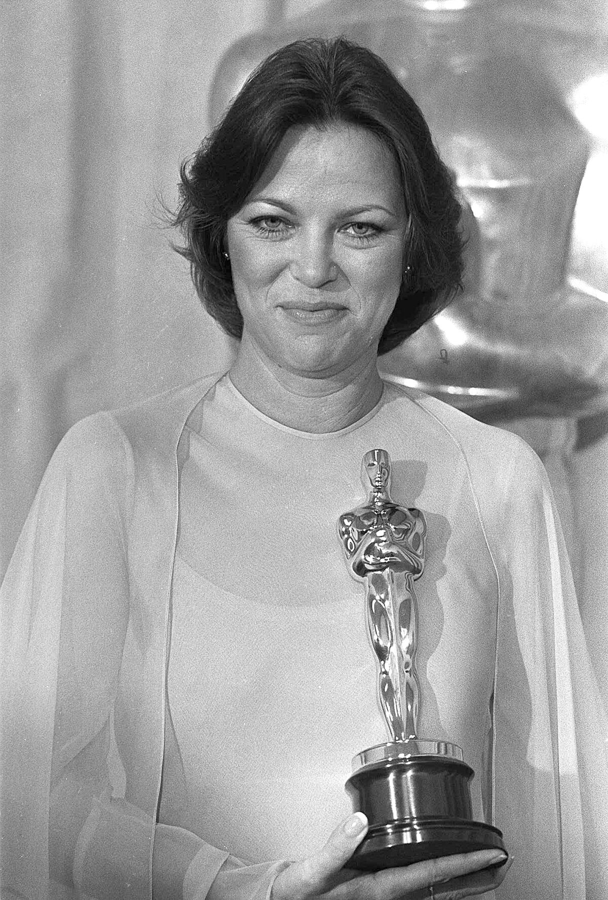 A woman in a gown holds an Academy Award