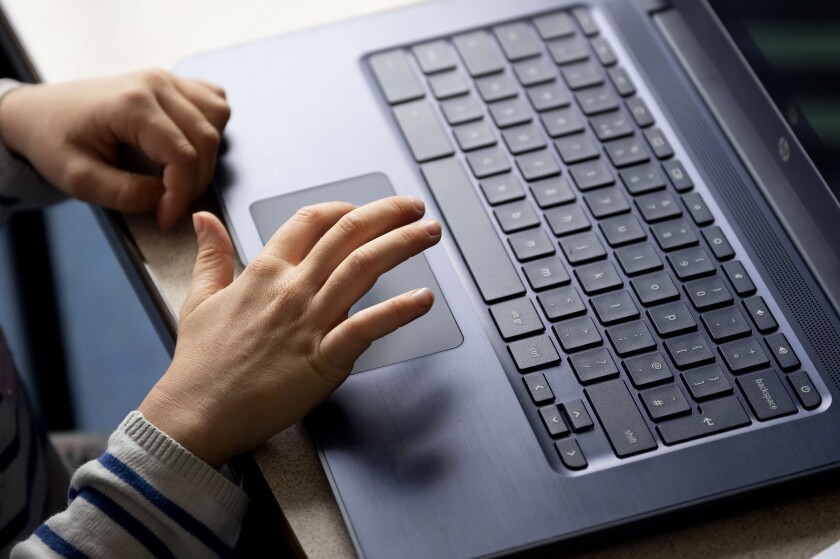 A close-up of a child's hands on a laptop