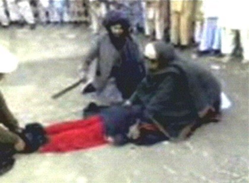In this undated image taken from mobile phone footage released by Dunya TV Channel shows a woman in a body-covering burqa face down on the ground with two men holding her arms and feet and a third man whipping her backside, on Friday, April 3, 2009. Pakistani authorities ordered an investigation Friday into a video showing a man flogging a screaming woman in the country's northwest where the government recently agreed to introduce Islamic law to end a rebellion by Taliban militants. (AP Photo/Dunya TV Channel)