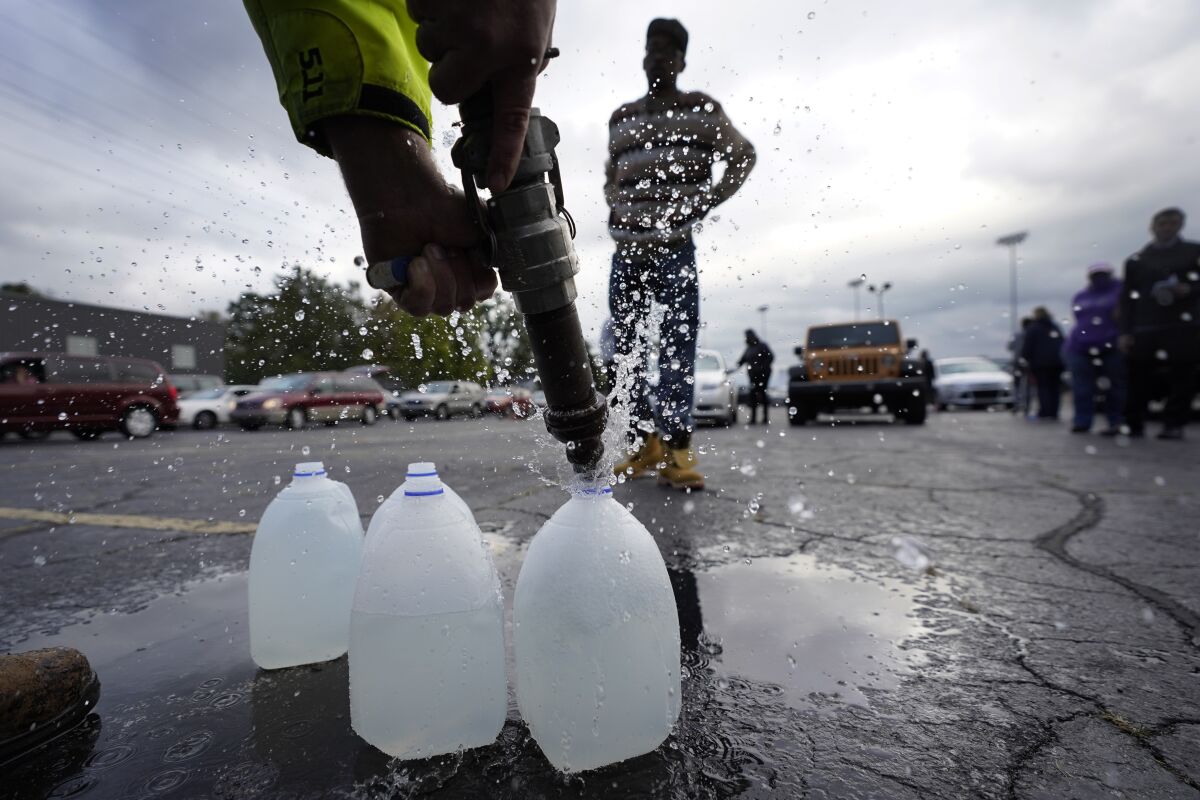 FILE - Kevin Stack with the Berrien County Road Department fills up jugs with non-potable water for Elliot Napier in the Benton Harbor High School parking lot Thursday, Oct. 21, 2021, in Benton Harbor, Mich. The water system in Benton Harbor has tested for elevated levels of lead for three consecutive years. In response, residents have been told to drink and cook with bottled water and the state has promised to spend millions replacing lead service lines. (AP Photo/Charles Rex Arbogast, File)