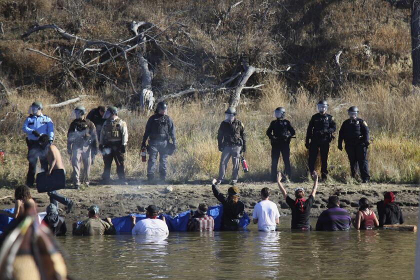 Dozens of protesters demonstrating against the expansion of the Dakota Access Pipeline wade in cold creek waters to confront local police.