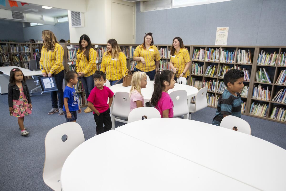 Representatives of IKEA watch as students check out the Paularino Elementary School library after it was revamped in 2018 with donated furnishings from the store. The Costa Mesa campus has been named a 2020 California Distinguished School.