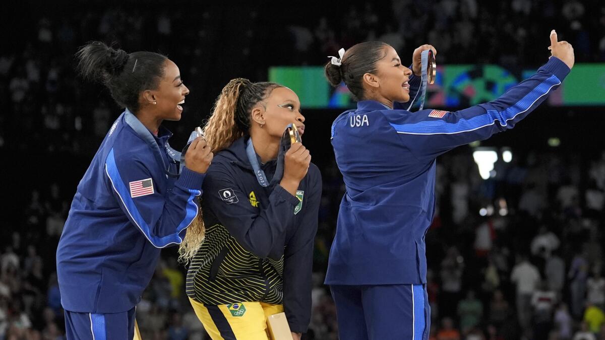 Rebeca Andrade celebrates after winning gold in the floor exercise, with Simone Biles and Jordan Chiles