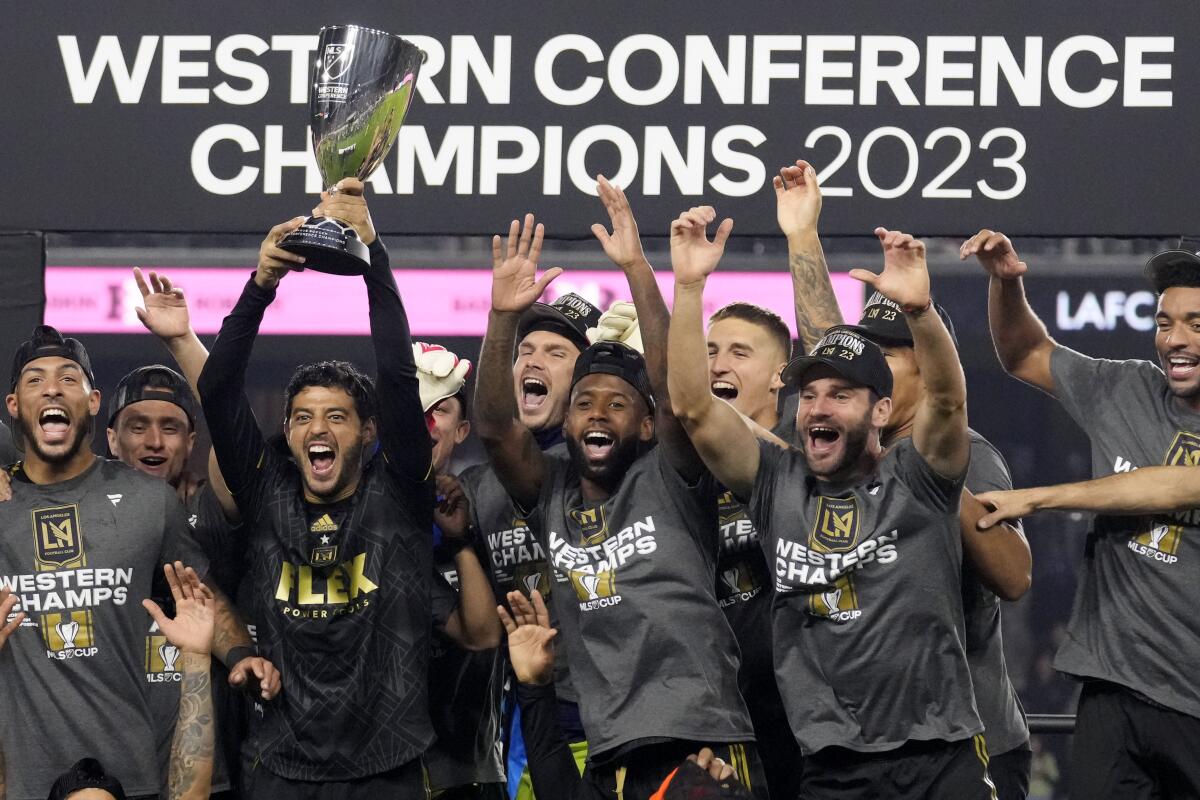 LAFC forward Carlos Vela is surrounded by celebrating teammates as he holds up the Western Conference final trophy
