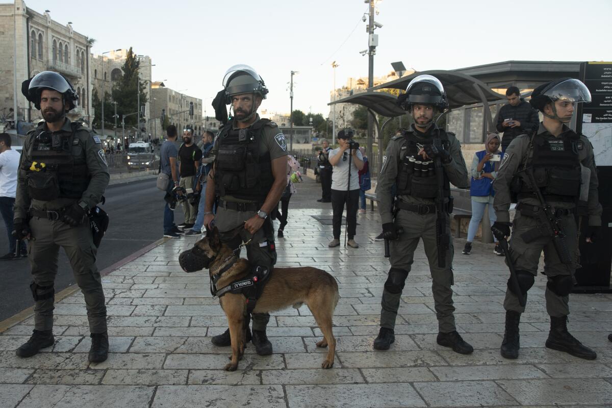 Israeli police and a police dog stand guard on the street.