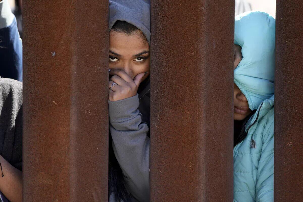 Dos migrantes que aguardan para solicitar asilo entre dos muros fronterizos