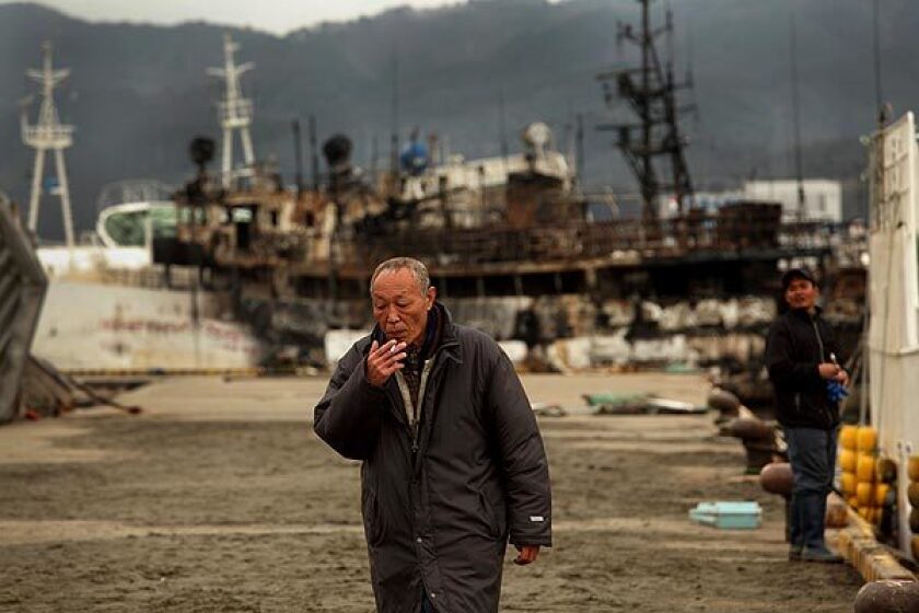 Fishing boat captain Tetsuyuki Hatakeyama walks along the pier in Kesennuma, Japan, where many boats were destroyed during the earthquake and tsunami that struck March 11. The boat behind him burned in the disaster.