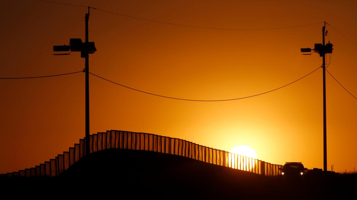 Sunset at the U.S.-Mexico border in Naco, Ariz., where a Border Patrol agents in his car keeps on activity.