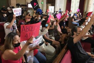 LOS ANGELES CA AUGUST 9, 2022 - Members of Services Not Sweeps, a local housing coalition, hold signs inside City Hall during council meeting, where a vote on expanding the 41.18 ordinance -- banning homeless encampments within 500 feet of schools and daycare centers is expected. (Genaro Molina/Los Angeles Times)