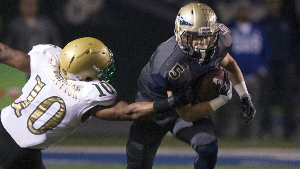 St. John Bosco running back Sean McGrew, right, carries the ball past Long Beach Poly's James Brooks Jr. during the Braves' division semifinal victory last season.