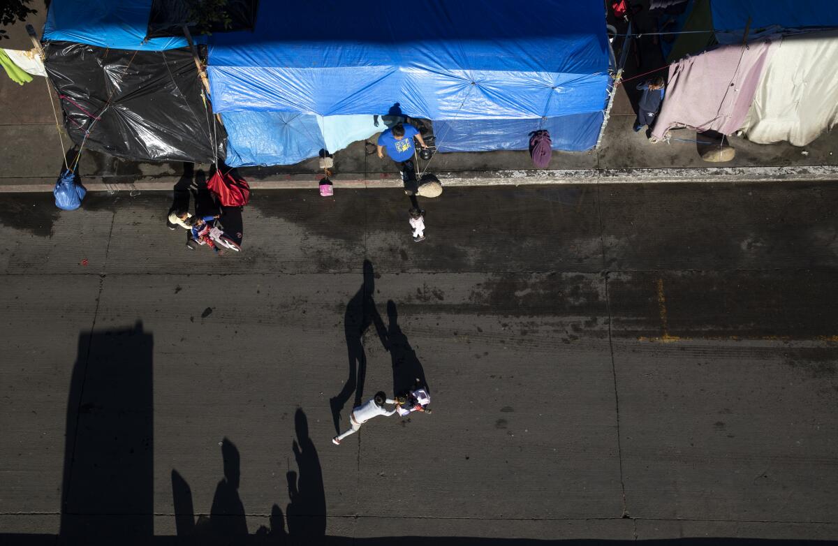 A man walks out of a tent while children play in the street
