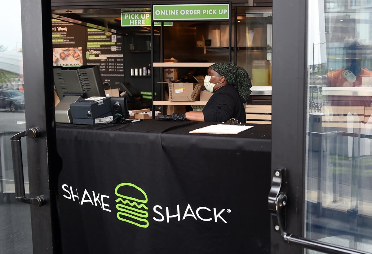 A woman prepares food orders in a Shake Shack